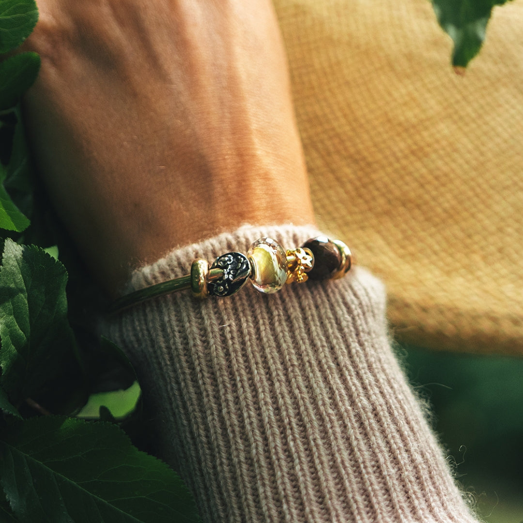 Model wearing a gold plated bangle with different beads